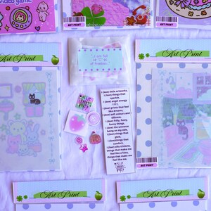 May include: An assortment of art prints and stickers in pastel colors. The prints feature cute illustrations of animals, rooms, and other whimsical designs. Some prints are packaged in clear plastic sleeves with polka dot borders. There is also a small bag of freebies.