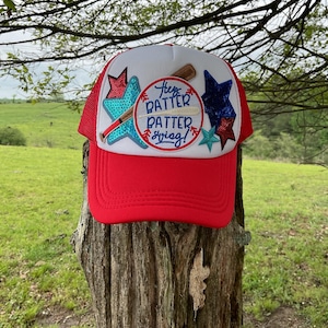 May include: Red and white baseball cap with a blue and white star and a baseball themed patch that says "Hey Batter Batter Swing!"