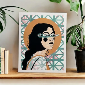 May include: A print of a woman with black hair and a brown halo. The woman's eyes are covered by a green and white banner with the text "DON'T LOOK AWAY". The background is a green and pink geometric pattern.