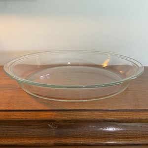 Op de afbeelding: Een heldere glazen taartvorm, perfect voor het bakken van taarten en andere desserts.