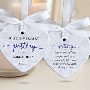 May include: Two heart-shaped tags with white ribbon bows. The tags have a floral pattern and text that reads "9th Anniversary pottery" with names and a date. The second tag has a poem about love.