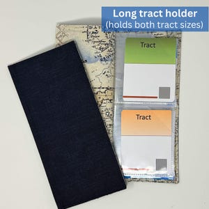 May include: A long tract holder with a navy blue cover and a map-themed interior. The holder contains two clear pockets with cards labeled "Tract" in green and orange. The text "Long tract holder (holds both tract sizes)" is visible.