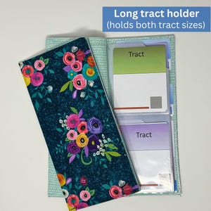 May include: A teal floral long tract holder with a colorful flower design. The holder is open, revealing clear pockets holding two tracts. The text "Long tract holder (holds both tract sizes)" is visible.