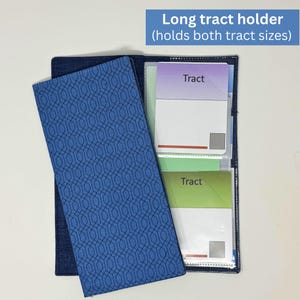 Könnte beinhalten: Ein langer Traktathalter aus blauem Stoff mit einem geometrischen Muster auf dem Umschlag. Der Halter ist geöffnet und zeigt mehrere Traktate mit dem Wort "Tract" darauf. Der Text "Langer Traktathalter (für beide Traktatgrößen)" steht oben.