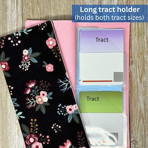May include: A long tract holder with a black floral pattern cover and pink polka dot interior. The holder contains several tracts with the word "Tract" printed on them. The text "Long tract holder (holds both tract sizes)" is visible.