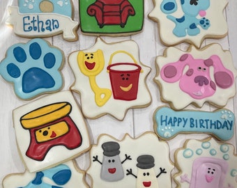 May include: A set of 10 decorated sugar cookies featuring characters from the children's television show Blue's Clues. The cookies are decorated with blue, pink, red, yellow, and green icing. The cookies include a paw print, a number 6, a book, a chair, a bucket, a shovel, a dog, a birthday message, and two characters from the show.