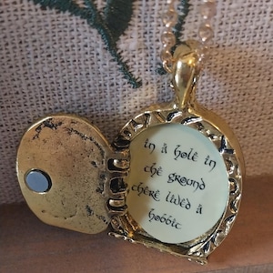Pu&ograve; includere: Una collana con un ciondolo d'oro con una citazione de Il Signore degli Anelli incisa all'interno: "In un buco nel terreno viveva uno hobbit".