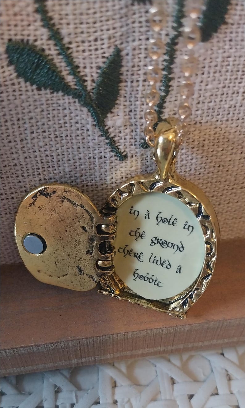 Pu&ograve; includere: Una collana con un ciondolo d'oro con una citazione de Il Signore degli Anelli incisa all'interno: "In un buco nel terreno viveva uno hobbit".