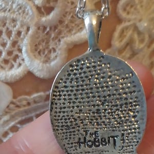 Pu&ograve; includere: Collana d'argento con un ciondolo rotondo che presenta un'immagine dettagliata di uno hobbit. Il ciondolo ha il testo "The Hobbit" inciso sul retro.