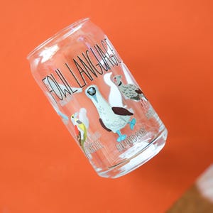 May include: A clear glass drinking glass with a design of various birds and the text "Fowl Language".