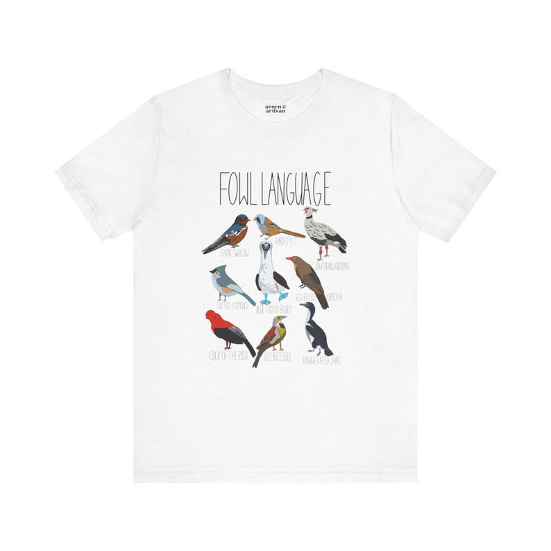 White unisex t-shirt with 'Fowl Language' bird design featuring tufted titmouse, blue-footed booby, and more. Flat lay on white background, perfect for bird lovers and humor fans.