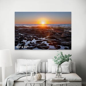 May include: A sunset over a rocky beach with tide pools reflecting the orange and purple sky. The image is 60 inches by 40 inches.