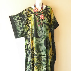 May include: A black and green kaftan with a floral print and a colorful beaded necklace. The kaftan has a short sleeve and a fringed hem.