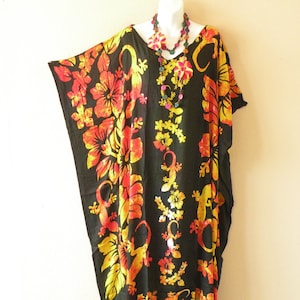 May include: Black kaftan with a floral print featuring yellow, orange, and red hibiscus flowers and lizards. The kaftan has a V-neck and short sleeves.