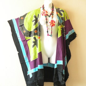 May include: A black, purple, green, and blue patterned kimono with a colorful wooden bead necklace. The kimono has a wide, flowing silhouette and is perfect for layering over a simple outfit.
