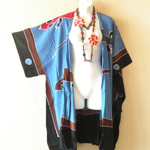 May include: A blue, brown, and black kimono-style robe with a colorful floral necklace. The robe features a unique pattern with red accents and is displayed on a white mannequin. The necklace has wooden beads and flower accents.