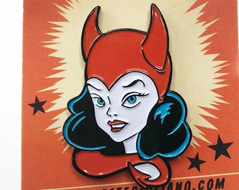 May include: A red and black enamel pin featuring a cartoon woman with red devil horns and a red dress. The pin is on a card with the text "Pin-ups by Celeste" and "www.celestegerolitano.com".