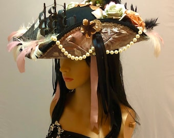 May include: A black and pink pirate hat with a pearl necklace, feathers, and floral embellishments.
