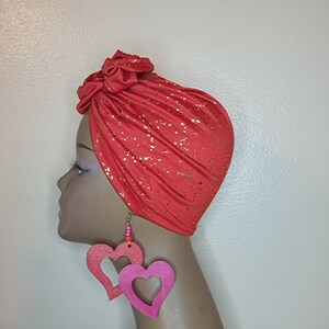 May include: A coral turban with gold glitter accents and a pair of pink heart-shaped earrings.