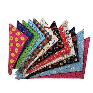 May include: A collection of 14 colourful dog bandanas with various patterns, including paw prints, bones and hearts. The bandanas are made of fabric and are triangular in shape.