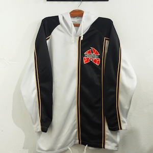 Puede incluir: Chaqueta con capucha blanca y negra con el texto "METHOD MAN" en rojo y amarillo. La chaqueta tiene un cordón en la parte inferior y rayas doradas a lo largo de los paneles negros. Cuelga de una percha de madera.