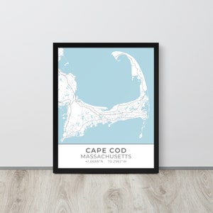 Puede incluir: Impresión enmarcada de un mapa de Cape Cod, Massachusetts, en un marco negro. El mapa presenta un fondo azul claro con carreteras y detalles terrestres blancos. El texto "CAPE COD MASSACHUSETTS" está impreso en la parte inferior, junto con las coordenadas.
