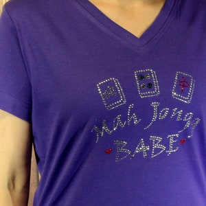 May include: Purple short-sleeved t-shirt with a rhinestone design that says "Mah Jongg Babe" with three mah jongg tiles.