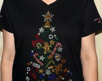 Könnte beinhalten: Schwarzes T-Shirt mit V-Ausschnitt und einem glitzernden Weihnachtsbaum-Design aus Strasssteinen. Der Baum ist mit Kugeln, Zuckerstangen und einem Lebkuchenmann verziert.