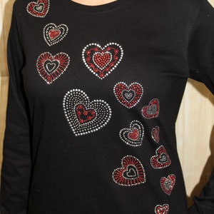 May include: Black long-sleeved shirt with a design of multiple red and silver hearts.