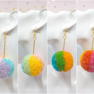 May include: Four pairs of rainbow pom-pom earrings with gold chains and hooks. The pom-poms are made of yarn and are in different color combinations.