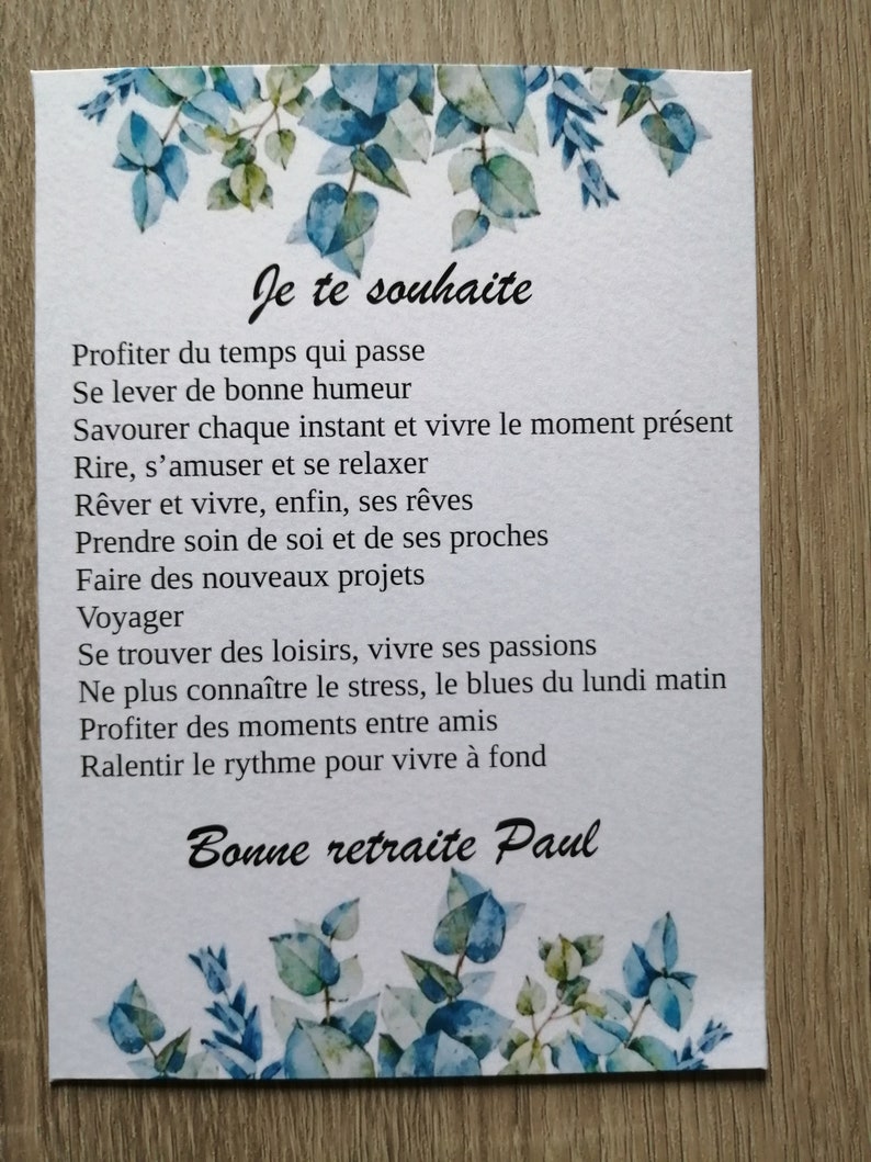 Pode incluir: Um cartão com um desenho floral azul e verde e o texto 'Je te souhaite' seguido de um poema sobre aproveitar a vida e a aposentadoria. O cartão termina com o texto 'Bonne retraite Paul'.
