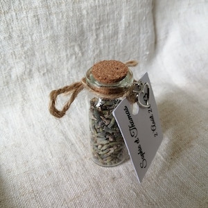 May include: A small glass bottle filled with dried lavender and tied with twine. A white tag with the text "Sophia & Thomas" and a heart charm is attached to the bottle.