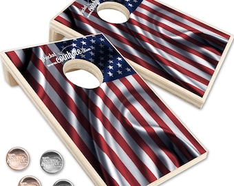 May include: Two wooden cornhole boards featuring the American flag design. Each board has a circular hole. Four metal bean bags are also present. The boards display the text "Pocket Cornhole" and a website address.