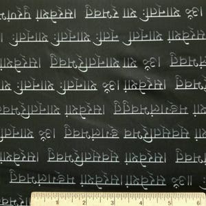 May include: Black fabric with white text repeating the phrase "Om Sarvesham Mangalam Bhavatu Om Shantah Shantah Shantah" in a Sanskrit-like font.