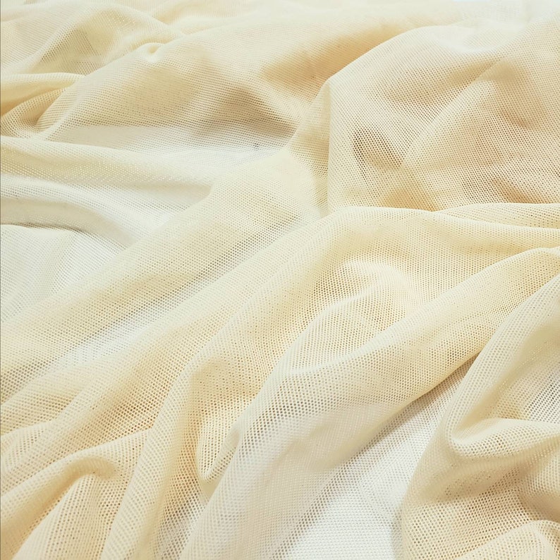 Pu&ograve; includere: Un primo piano di un tessuto a rete beige con una trama fine e uniforme. Il tessuto &egrave; morbido e cade bene, rendendolo ideale per una variet&agrave; di progetti di artigianato.