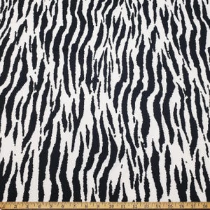 Può includere: Tessuto a stampa zebra bianco e nero. Il tessuto ha una texture liscia e setosa.