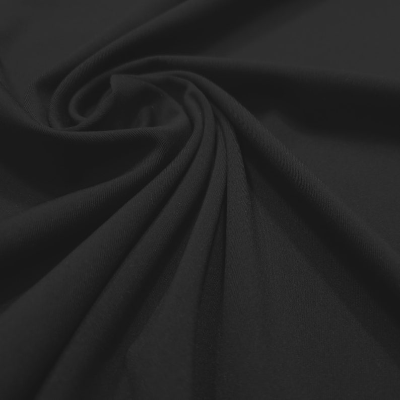 May include: A close-up shot of black fabric with a soft, flowing texture. The material is draped and swirled, creating a pattern of shadows and highlights. The fabric appears to be a solid color, with no visible patterns or designs.