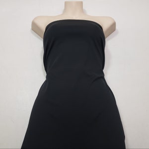 May include: A black strapless dress displayed on a mannequin. The dress is made of a smooth, solid fabric and has a simple, elegant design. The dress is a versatile piece suitable for various occasions.