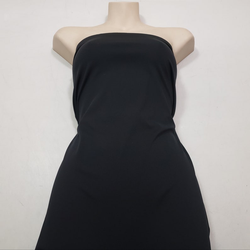 May include: A black strapless dress displayed on a mannequin. The dress is made of a smooth, solid fabric and has a simple, elegant design. The dress is a versatile piece suitable for various occasions.