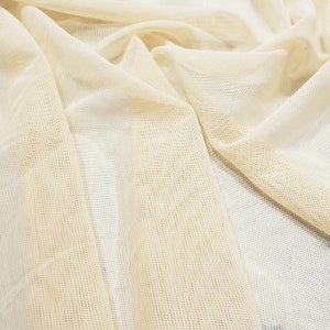 Pu&ograve; includere: Tessuto a rete color crema con una trama fine e uniforme. Il tessuto &egrave; morbido e leggero, con una superficie leggermente strutturata.