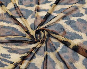 May include: A sheer fabric with a brown and black leopard print pattern. The fabric is draped and twisted, showing the texture of the material.