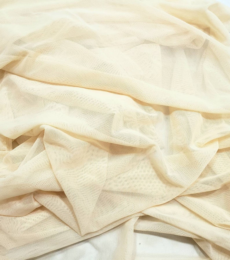 Pu&ograve; includere: Un primo piano di un tessuto beige trasparente con una trama a rete fine. Il tessuto &egrave; piegato e drappeggiato, mostrando la sua qualit&agrave; delicata e ariosa.