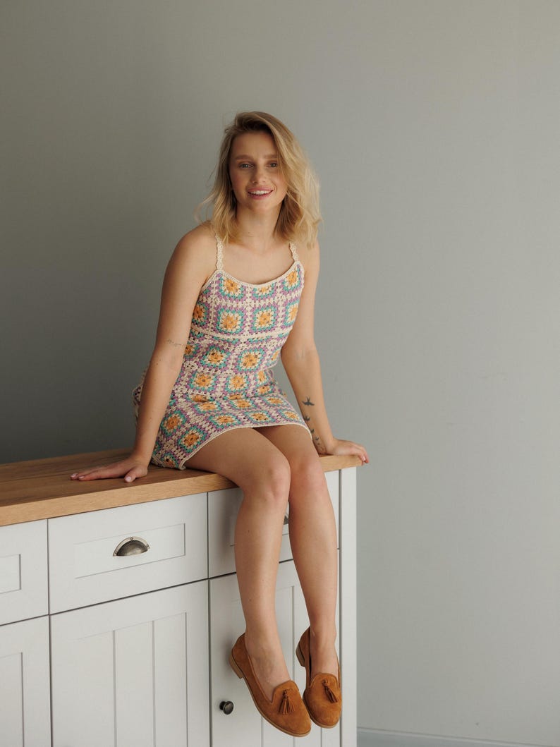 K&ouml;nnte beinhalten: Ein buntes H&auml;kelkleid mit quadratischem Muster in Pastellfarben. Das Kleid hat d&uuml;nne Tr&auml;ger und wird mit braunen Loafern kombiniert. Das Kleid ist ein Mini-Kleid-Stil, perfekt f&uuml;r den Sommer oder einen l&auml;ssigen Ausflug. Das Kleid ist ca. 70 cm lang.