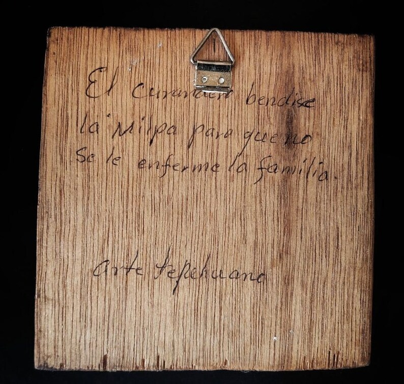 May include: A wooden plaque with a handwritten message in Spanish. The message reads "El  Creador bendise la Milpa para que no se le enferme la familia.  Arte Tepichana."