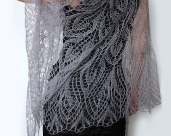 May include: A delicate gray knitted shawl with a lacy pattern. The shawl is draped over a person's shoulders and is made of a lightweight, airy fabric.