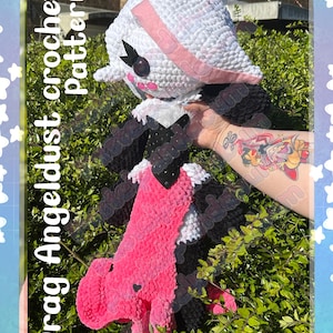 May include: A handmade crochet doll with a white head, pink accents, and black details. The doll has a pink body and black wings. Text on the image reads "Drag Angeldust crochet Pattern" and "Pastelpandabum".
