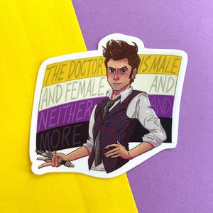 以下が含まれることがあります： チェック柄のベストと白いシャツを着て、デバイスを持っている人の漫画イラストが描かれたステッカー。ステッカーには「THE DOCTOR IS MALE AND FEMALE AND NEITHER MORE」と書かれています。背景はノンバイナリープライドフラッグです。