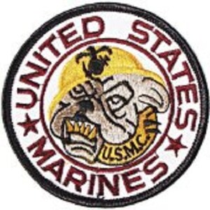 Könnte beinhalten: Ein runder, schwarz-weißer Aufnäher mit den Worten "United States Marines" in roten Buchstaben am Rand. In der Mitte befindet sich ein Cartoon-Bulldog mit gelbem Hintergrund und den Worten "USMC" in gelben Buchstaben.