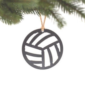 May include: Black and white volleyball ornament hanging from a brown twine string. The ornament is made of wood and has a cut-out design of a volleyball.