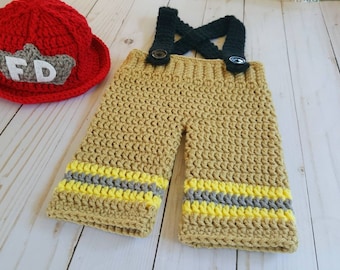 May include: Crocheted firefighter costume for a baby, featuring a red hat with the letters "FD" and tan pants with yellow and gray stripes.